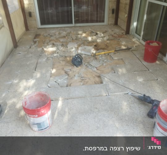 רצפה שבורה עם כלים ודלי במהלך שיפוץ